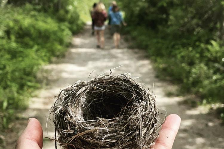 person holding birds nest with students in the background